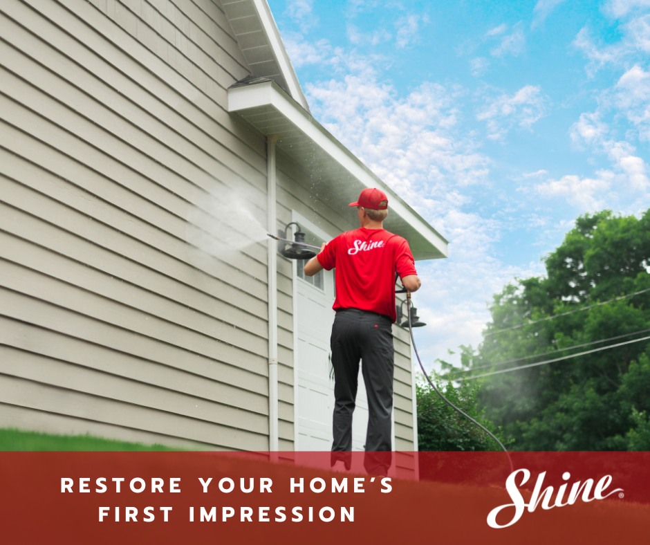 Shine technician pressure washing home siding on a bright day
